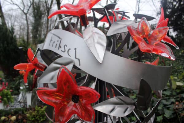 Eigentijds grafmonument met prachtige rode glazen bloemen voor partner