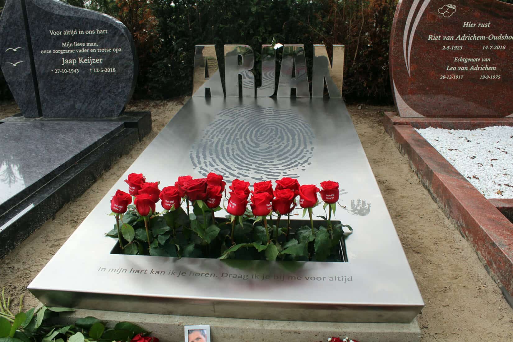Abstract grafmonument van RVS met rode rozen