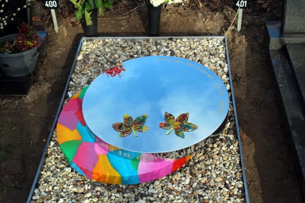 Modern grafmonument van rvs met kleur en bladeren