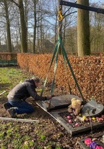 Plaatsing van een grafzerk met hijsbanden op een babygraf