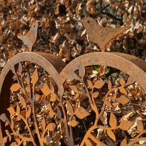 Detail van twee vogeltjes boven op een cortenstalen hart.
