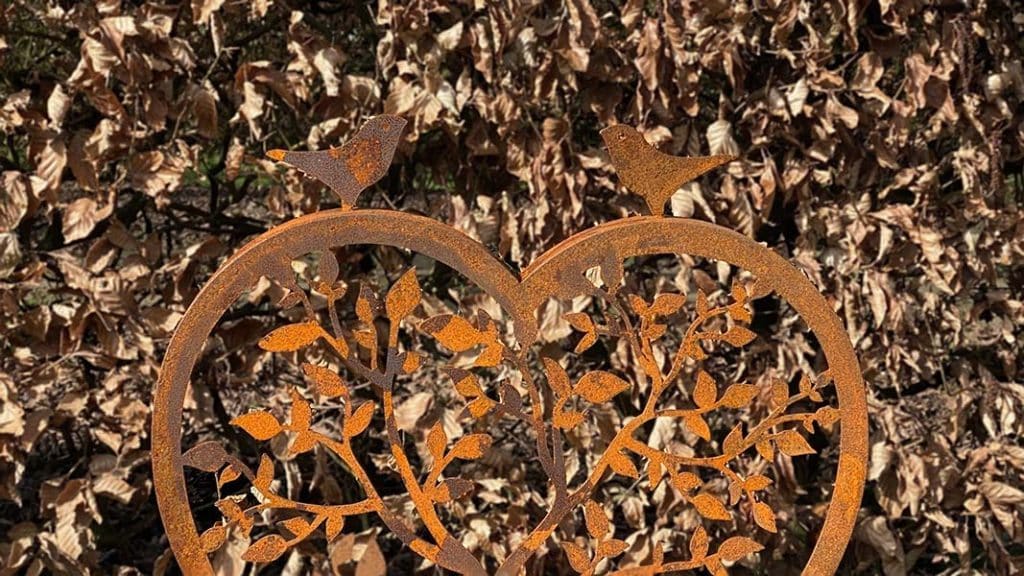 Twee vogeltjes boven op een hart van cortenstaal
