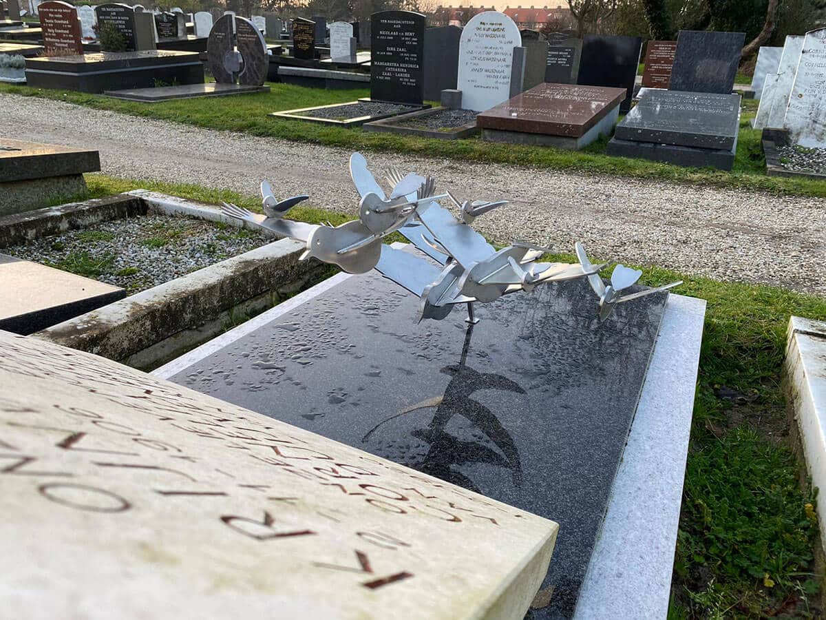 Traditionele grafsteen met grafkunst eigentijdse RVS vogels