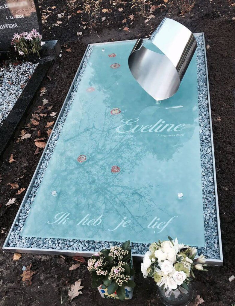 Moderne Grafzerk van glas en RVS met voetafdrukken en bloemen