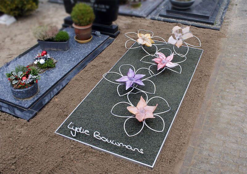 Eigentijds en abstract grafmonument met RVS en glazen bloemen voor jonge vrouw en naam in eigen handschrift